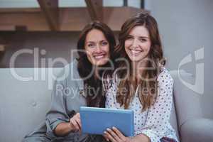 Two beautiful women using a digital tablet in living room