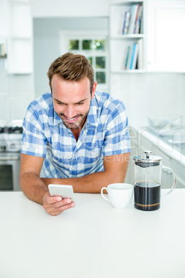 Man using mobile phone while leaning on table