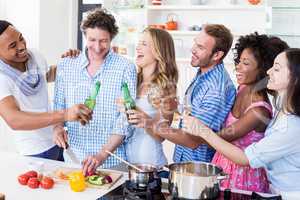 Group of friends toasting beer and wine glasses in kitchen