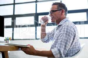 Man having glass of water and holding digital tablet