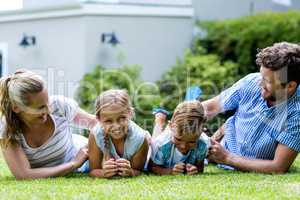 Happy parents tickling children in yard