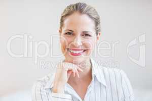 Happy businesswoman sitting with hand on chin