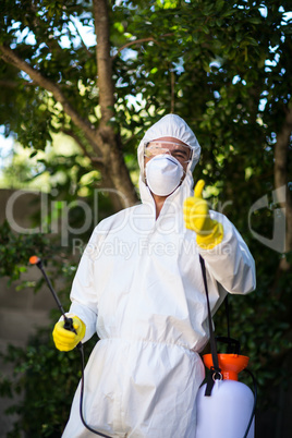 Man showing thumbs up while holding pesticide sprayer