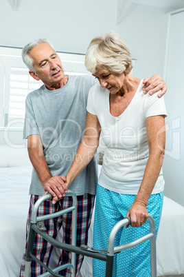 Aged woman with walker by man in bedroom