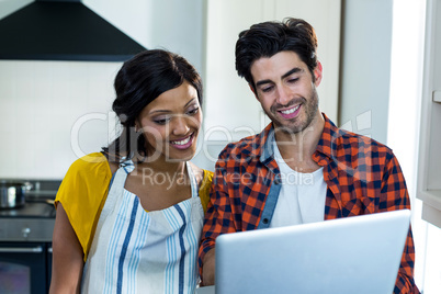 Young couple using laptop in kitchen