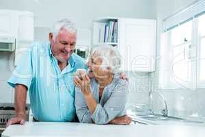 Happy senior woman showing phone to man