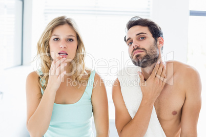 Man and woman checking their skin in bathroom