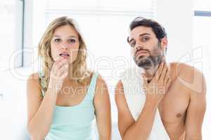 Man and woman checking their skin in bathroom