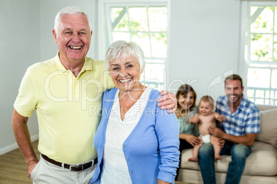 Happy senior couple with family sitting in background