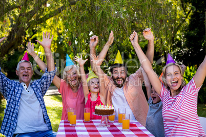 Family with arms raised enjoying birthday at yard