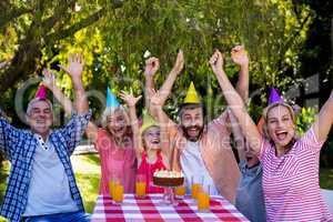 Family with arms raised enjoying birthday at yard