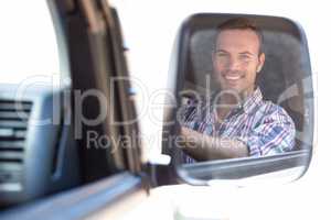 Young man driving with his reflection in rear view mirror