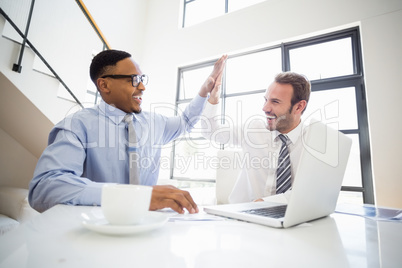 Businessmen giving a high five while at a meeting