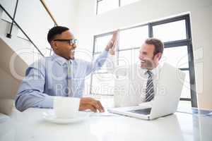 Businessmen giving a high five while at a meeting