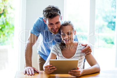 Smiling man and woman looking at digital tablet