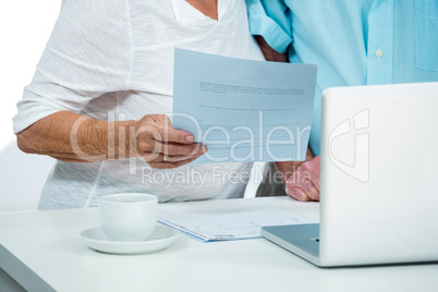Midsection of senior woman with man holding document