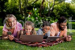 Family using technologies while lying at yard