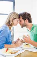 Young couple toasting wine glasses while having meal