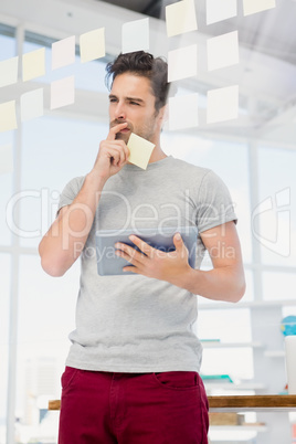 Thoughtful man holding digital tablet and sticky notes