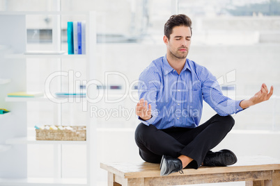 Businessman meditating in lotus pose