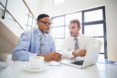 Businessmen looking at laptop and interacting in office