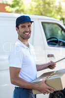 Cheerful delivery man carrying cardboard box