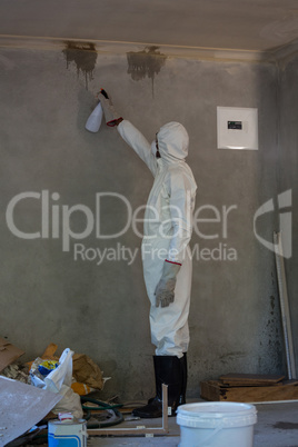 Man doing pest control on a wall