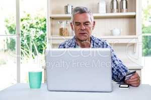 Senior man shopping online using laptop