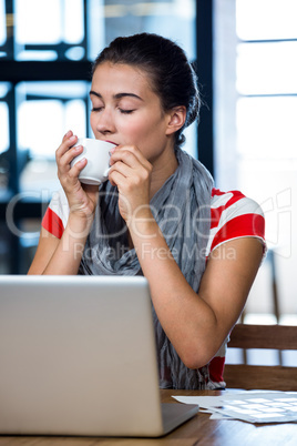 Woman having coffee with digital tablet on table