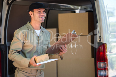 Happy delivery man holding cardboard box and clipboard