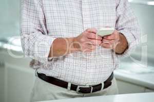 Midsection of senior man text messaging on mobile phone