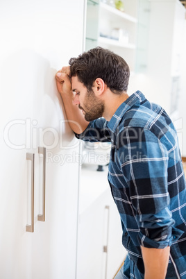 Depressed man leaning his head against a door