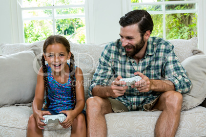 Happy father looking at daughter while playing video game at hom