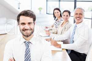 One businessman is standing and three workers are sitting and sm