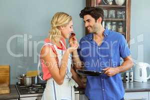 Man feeding his woman in kitchen
