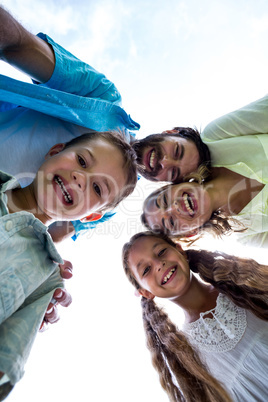 Cheerful family forming huddle against sky