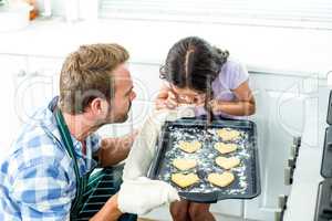 Father holding tray while daughter looking at cookies