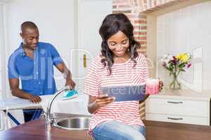 Young woman holding coffee mug and using digital tablet