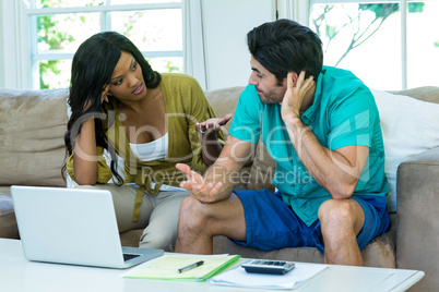 Worried young couple with laptop discussing on bills