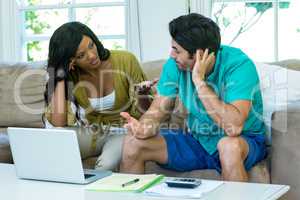 Worried young couple with laptop discussing on bills
