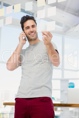 Man looking at a sticky notes while talking on phone Man looking at a sticky notes while talking on phone