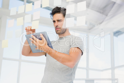 Man holding digital tablet and looking at sticky notes Man holding digital tablet and looking at sticky notes