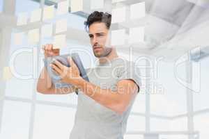 Man holding digital tablet and looking at sticky notes