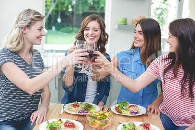 Friends toasting glass of red wine while having meal