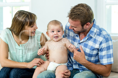 Parents with cute baby boy on sofa