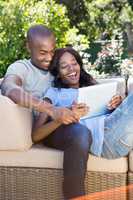 Young couple relaxing on the sofa and using digital tablet