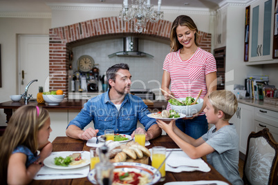 Woman serving food to her family in the kitchen