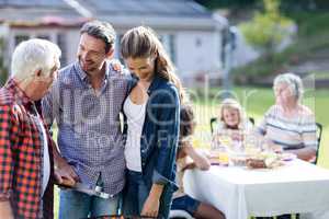 Couple and a senior man at barbecue grill preparing a barbecue