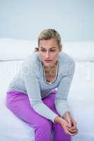 Thoughtful woman sitting on bed