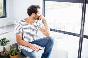 Man sitting with laptop looking out through window